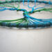 bottom of tree show roots anchored to teal color yarn wrapped metal hoop